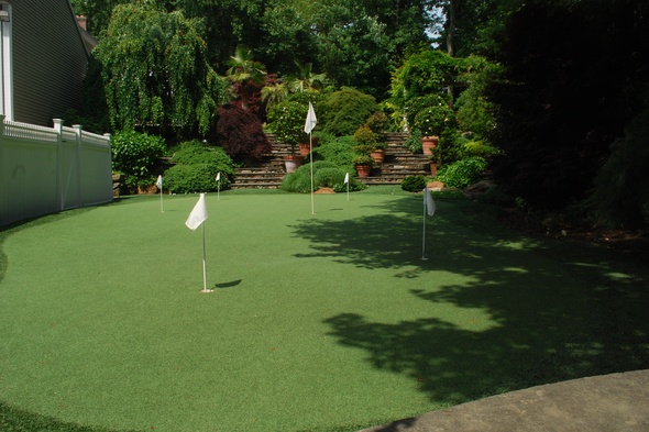 Flagstaff Synthetic grass golf green with flags in a landscaped backyard