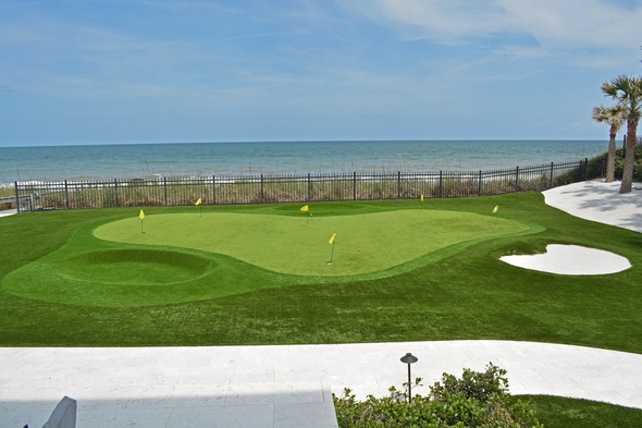 Flagstaff Synthetic grass golf green by the sea with yellow flags and a sand bunker