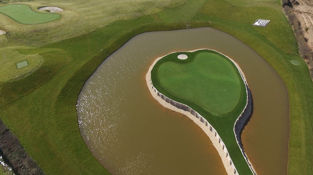 Flagstaff Aerial view of a vibrant green synthetic grass island in a natural pond on a golf course